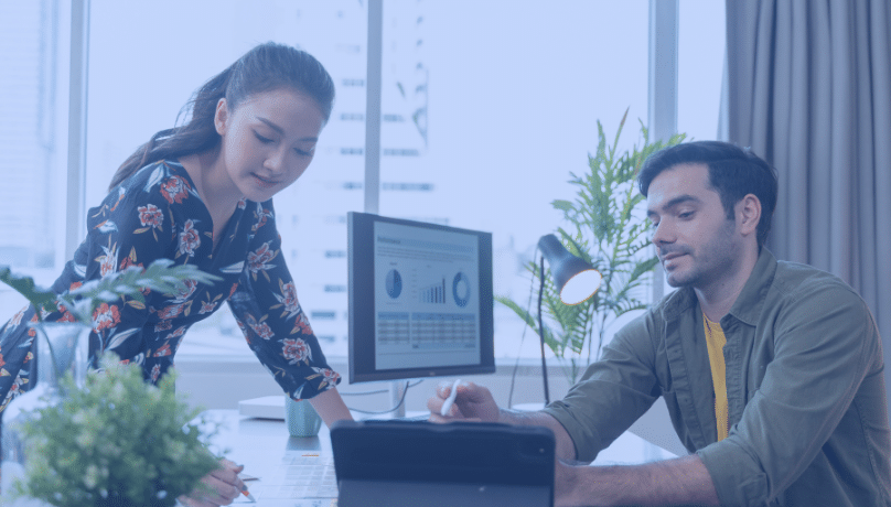 A man and woman work together on a laptop in an office, focusing on selecting a software development consulting partner.
